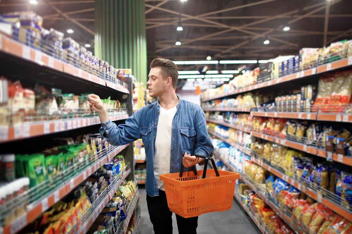 young white man shops  in store aisle for health and wellness products