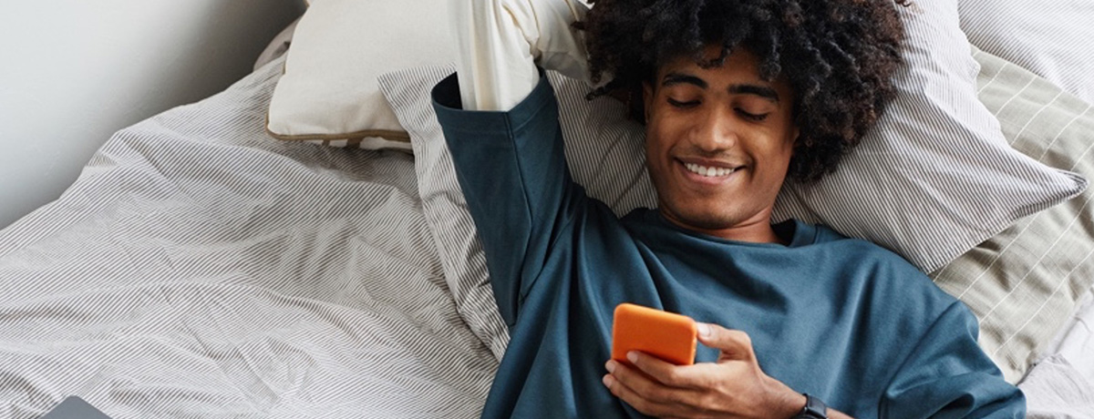 Young man laying down looking at this phone